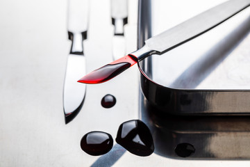 Surgical steel scalpels on stainless steel table with blood