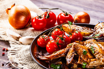 Roast chicken wings, baked potatoes and vegetables