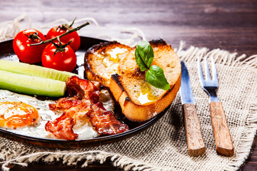 Breakfast - fried egg ,toasts,bacon, and vegetables