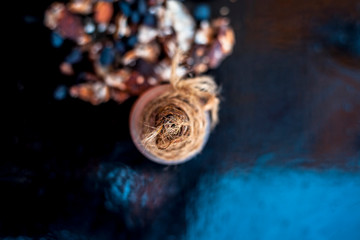 Tamarind or imli or amli in a clay bowl along with its roasted seeds and extract essential oil in a glass bottle on wooden surface.