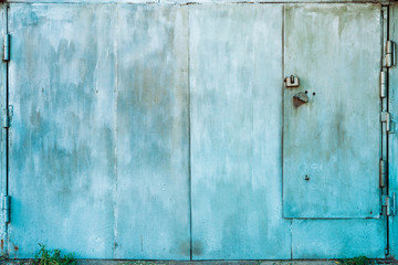 Closed imperfect rust metallic garage gate close-up. Damage texture of locked rusty iron door. Grungy metal surface. Textured background of rough faded uneven steel gates. Obsolete metal surface.