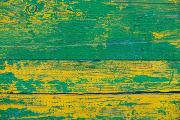 Old wooden painted rustic wall with yellow green flaky dye. Faded wood plank close-up. Peeling paint on board. Damaged rough wooden texture. Imperfect wood surface. Background with weathered paint.
