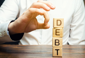 Businessman removes wooden blocks with the word Debt. Reduction or restructuring of debt....