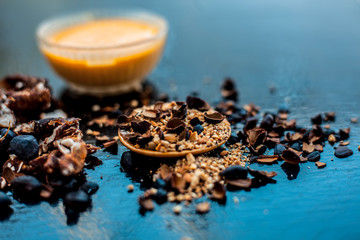 Tamarind or imli or amli in a clay bowl along with its roasted seeds and extracted paste or tincture in a glass bowl along with powder of roasted tamarind seeds on wooden surface.