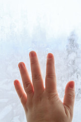 Hand on frozen winter cold window with patterns