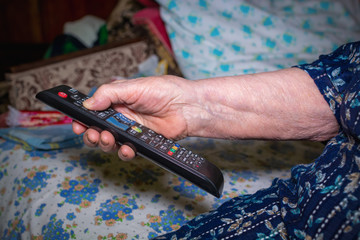 Elderly woman operating TV or DVD with remote control.
