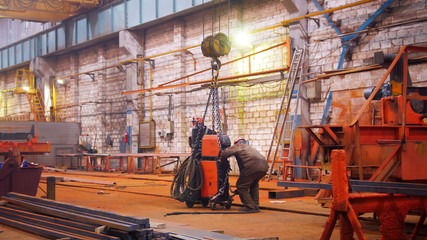 Industrial concept. A crane put down the orange detail on the floor and man worker taking it