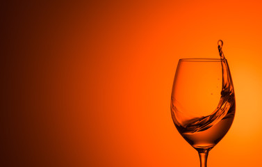 splash of water in a glass on an orange background. A glass of water on a orange background. 
