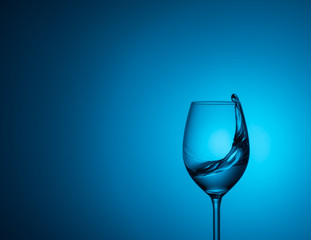 a glass of water stands on acrylic glass on a blue background.water is poured into a glass,splash of water 