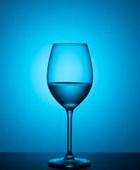 a glass of water stands on acrylic glass on a blue background.