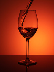 splash of water in a glass on an orange background. A glass of water on a orange background. 