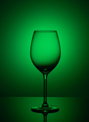 Empty wine glass is on acrylic glass, on a green background