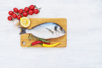 Fresh dorada fish with spices on wooden cutting board. Healthy food concept. Top view, copy space.