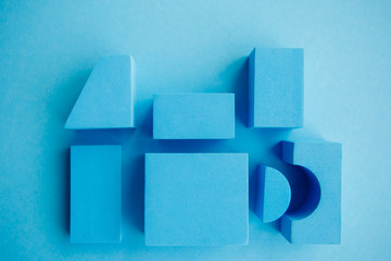 Geometrical figures still life composition. Cube and other objects on blue background. Simplicity concept photography