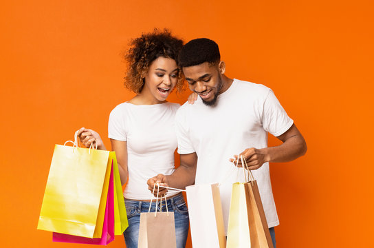 Happy Black Couple Looking Into Shopping Bags