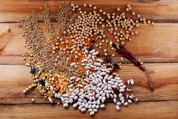 Mixed dried legumes and cereals isolated on wooden background, top view