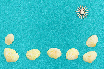 Fototapeta na wymiar Seashells and wood sun on a turquoise glitter background
