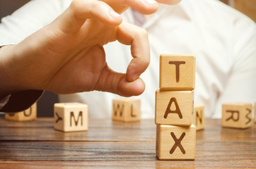 Businessman removes wooden blocks with the word Tax. The concept of reducing the tax burden. Tax...