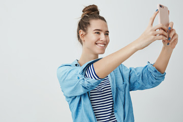 Girl knows best angle taking selfie. Studio shot good-looking fashion female blogger recording video followers talking beauty stylish tips, smiling holding smartphone capturing new look outfit
