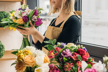 Cropped view of florist in apron holding bouquet in flower shop