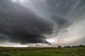 Naklejka na ściany i meble A wall cloud forms underneath a supercell storm, over fields of sagebrush.