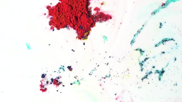 Colorful dry ink moving on white milk background, top view. Close up for powder paint floating on the surface of white liquid, art concept.