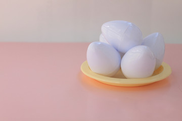 White eggs on the background in pink pastel color. Small plastic toy eggs. Kids toys. Minimalism food concept. Easter concept.Pink and white background.