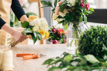 Partial view of florist making bouquet in flower shop