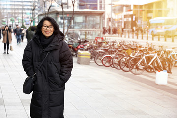 Asian old lady Wearing a sweater Overcoat black With a background image of a building in the city