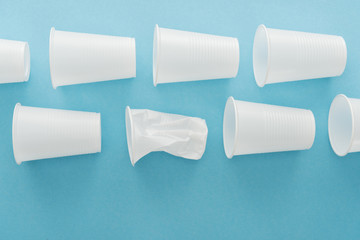 top view of white crumpled plastic cups on blue background with copy space