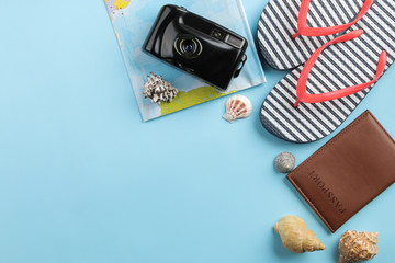 Naklejka premium Travel concept. Passport, camera, flip flops, map and glasses on a bright blue background. top view. space for text