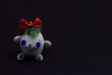 Exclusive kind fairy character made from chicken eggs and willow buds with bright red bow on black background. Concept — fantasy and imagination. Minimal style.