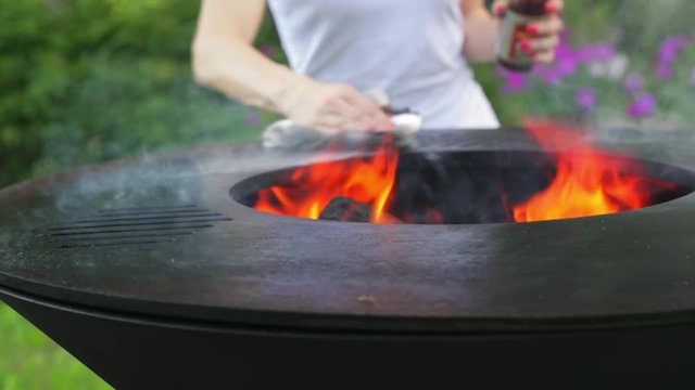 Preparing a new grill for use. Linseed oil on a white cloth. Use of oil for the first calcination of the frying surface. Female hand with a manicure. Happy people having camping and bbq party outdoor.