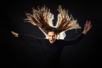 Emotional portrait of a girl with long curly hair on a black background,