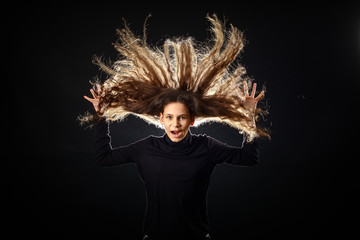 Emotional portrait of a girl with long curly hair on a black background,