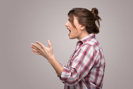 Profile Of An Angry Rage Young Woman Shouting Isolated On A Gray