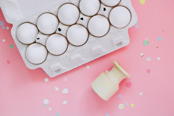 Easter concept, flat lay chicken eggs and vibrant confetti on pink background. Top view.