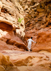 man in white arab clothing walks in a colored canyon in Egypt Dahab South Sinai