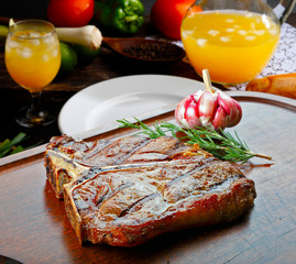 T bone steak with trimmings, potato, salad, orange juice, bread