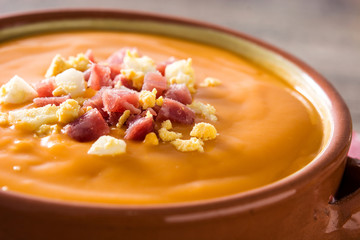 Typical Spanish salmorejo cream with ham and egg on wooden table. Close up