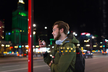 Young man using smartphone on urban street at night