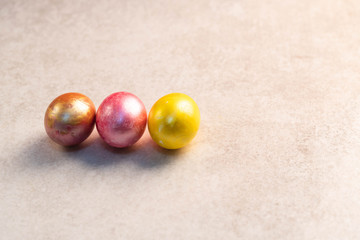 Colourful Easter eggs, pink, orange and yellow colour on a light marble backdrop