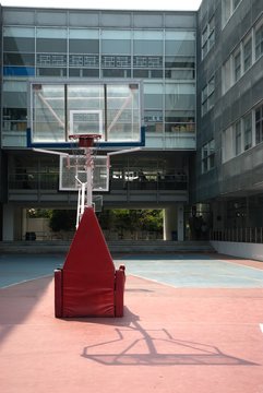 A red basketball hoop with white rope net  on the childrens playground in the school.