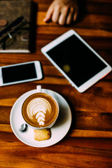 The hand of a man sitting at a table with a cup of aromatic coffee, a telephone and a notebook. Business lunch