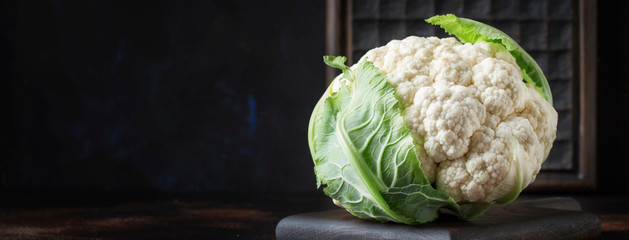 Fresh whole cauliflower on brown kitchen table background, banner, selective focus