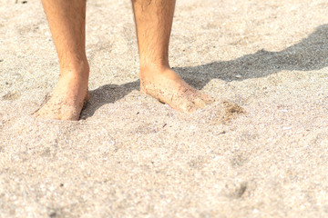 Closeup view of bare human feet on sand beach background. Summer vacation concept 