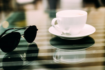 The hand of a man sitting at a table with a cup of aromatic coffee, a telephone and a notebook. Business lunch