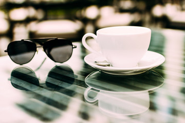 The hand of a man sitting at a table with a cup of aromatic coffee, a telephone and a notebook. Business lunch