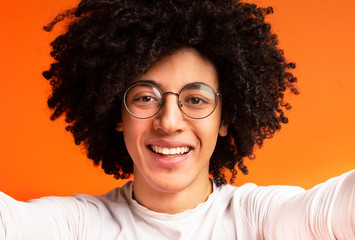 Obraz premium Cheerful millennial african-american guy making selfie on orange
