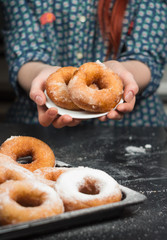 a girl in a vintage shirt with donuts, donuts on a plate, drzhit puffs in her hand, donuts in powdered sugar, donut in hand